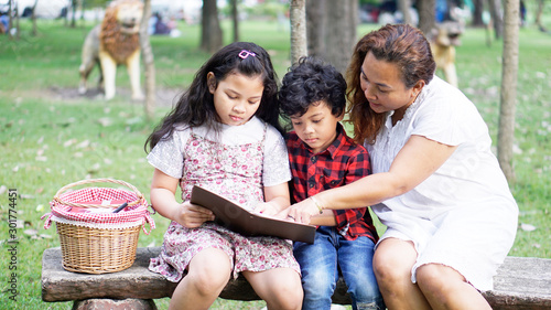 Asian families sit in the garden, read books for their daughter and son holidays, happy mother's day or family holiday. 