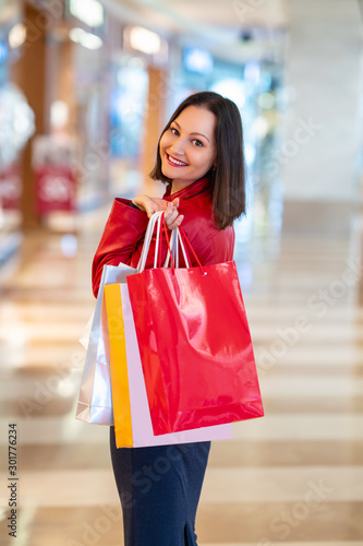 Young woman is walking in a mall and is shopping with a happy smile