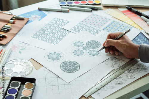 Designer designing drawing sketch pattern geometric flower seamless wallpaper fabric textile fashion industry. artistic design studio..