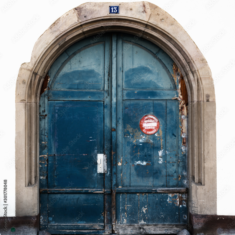 detail view of a large blue arched wooden doorway with a sign in French saying detail view of a large blue arched wooden doorway with a sign in French saying