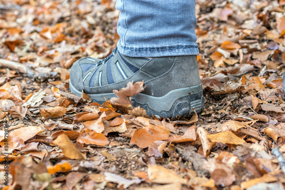 Schuh eines Mannes der über einen herbstlichen Waldboden läuft Schuh eines Mannes der über einen herbstlichen Waldboden läuft