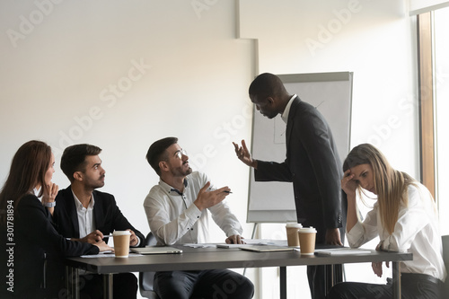 Multiracial colleagues argue at company meeting in office