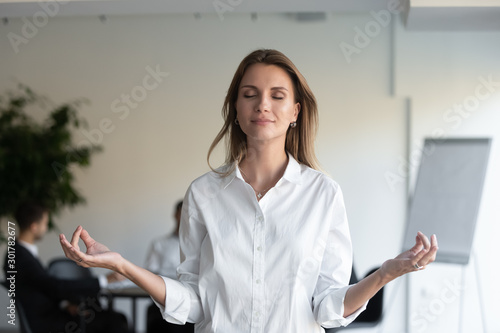 фотографія Calm businesswoman meditate relieving negativity at workplace