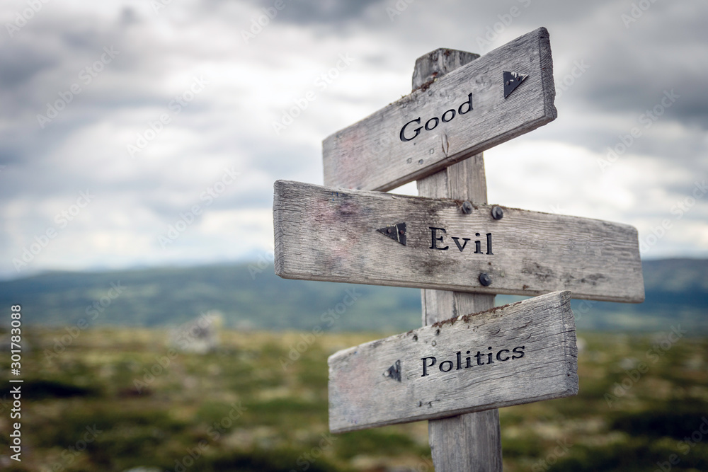 Good, evil and politics text on wooden sign post outdoors in landscape scenery. Business, quotes and motivational theme concept.