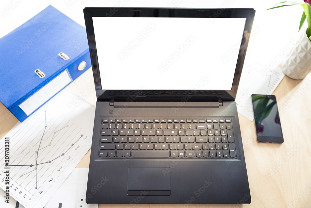 Blank screen laptop on wooden table with ring binder, mobile phone and some papers with diagrams - business, website concept Blank screen laptop on wooden table with ring binder, mobile phone and some papers with diagrams - business, website concept