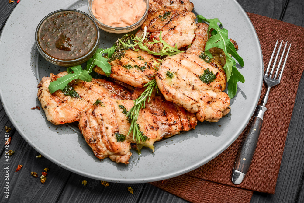Tasty Grilled chicken fillet and chili peppers on a plate on the table. horizontal view from above Tasty Grilled chicken fillet and chili peppers on a plate on the table. horizontal view from above