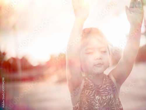 Fototapete Little girl praying and raise hands in the morning for faith, spirituality and religion