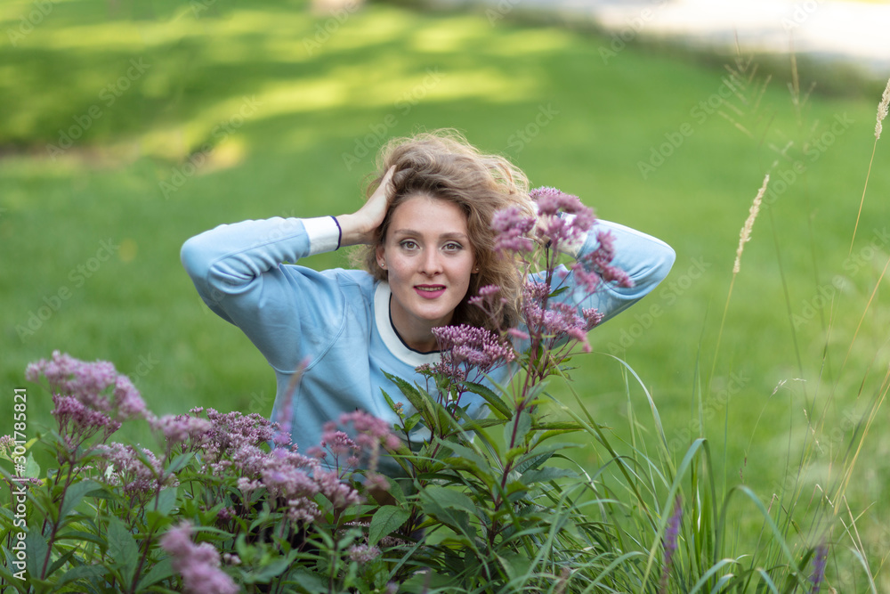 Girl on the green lawn. Smile, flowers on a background of a city park. Girl on the green lawn. Smile, flowers on a background of a city park.