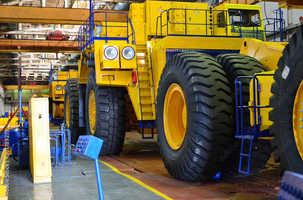 Production process of heavy mining trucks at the factory. Dump truck on the Industrial conveyor in the workshop of an automobile plant. Manufacturer of haulage and earthmoving equipment, haul trucks