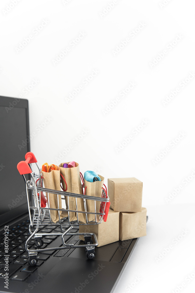 Shopping cart with purchases - packages and boxes on the modern laptop. Online shopping, black friday and sale concept.