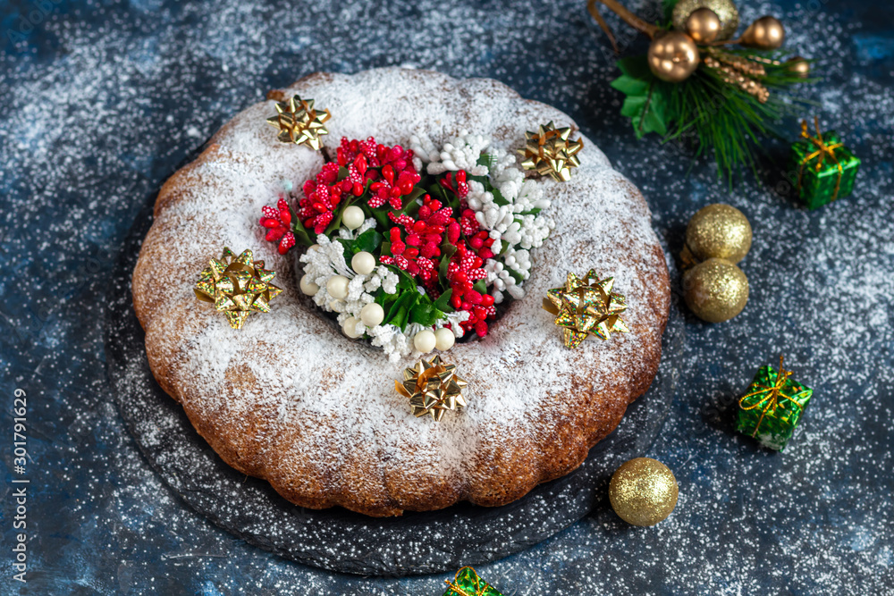 Christmas, holiday muffin sprinkled with powdered sugar. Decorated with New Year's toys. On a dark background. Copy space. 