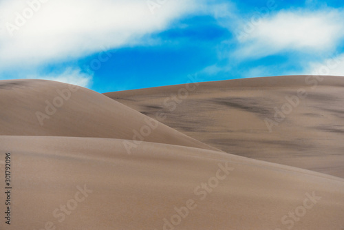 Sand dunes whith dark lines under a cloudy sky. © Oleksiy