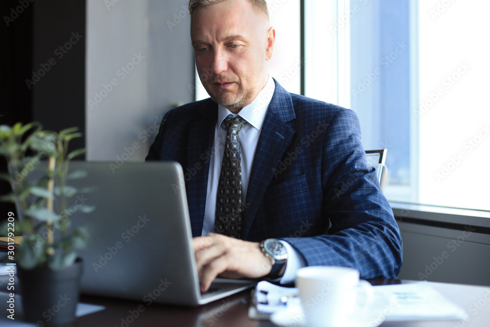 Focused mature businessman deep in thought while sitting at a table in modern office. Focused mature businessman deep in thought while sitting at a table in modern office.