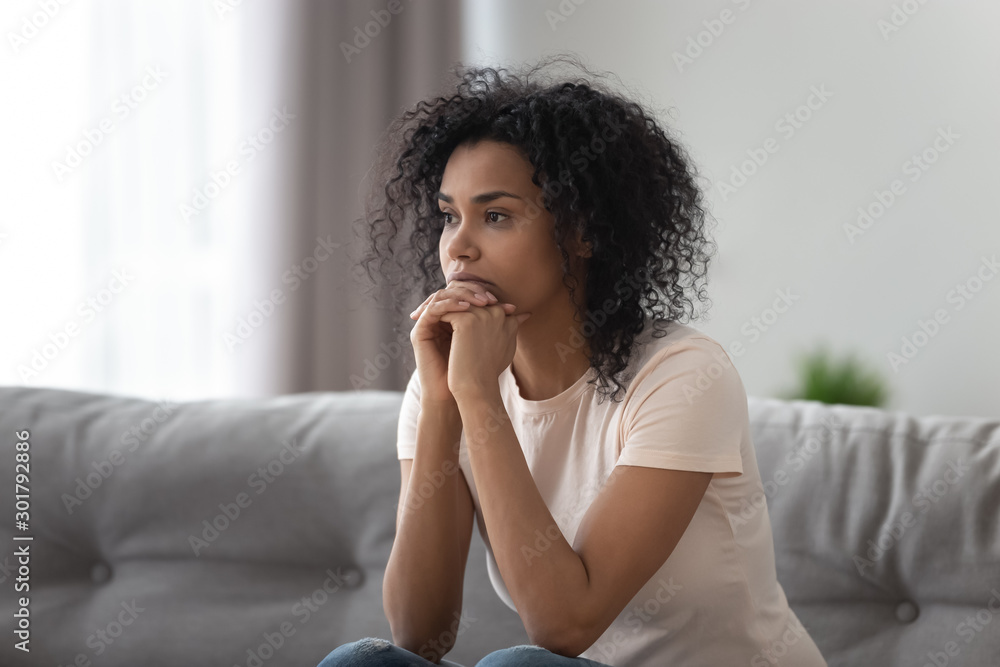 © fizkes - Upset African American woman thinking about problem at home alone