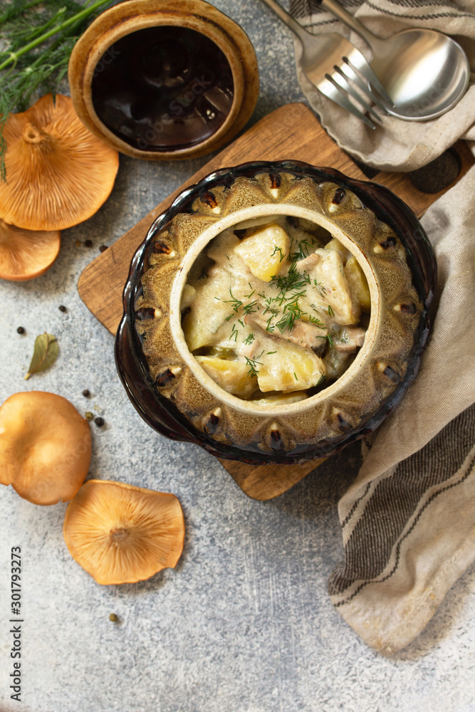 Red mushrooms with stewed potatoes, sour cream and spices in a ceramic pot on a stone countertop. Top view flat lay background with copy space. Red mushrooms with stewed potatoes, sour cream and spices in a ceramic pot on a stone countertop. Top view flat lay background with copy space.