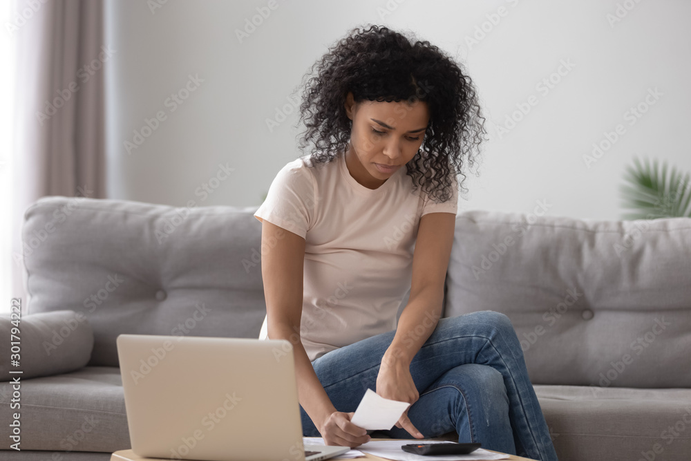 Serious African American woman using laptop, calculating finance at home Serious African American woman using laptop, calculating finance at home