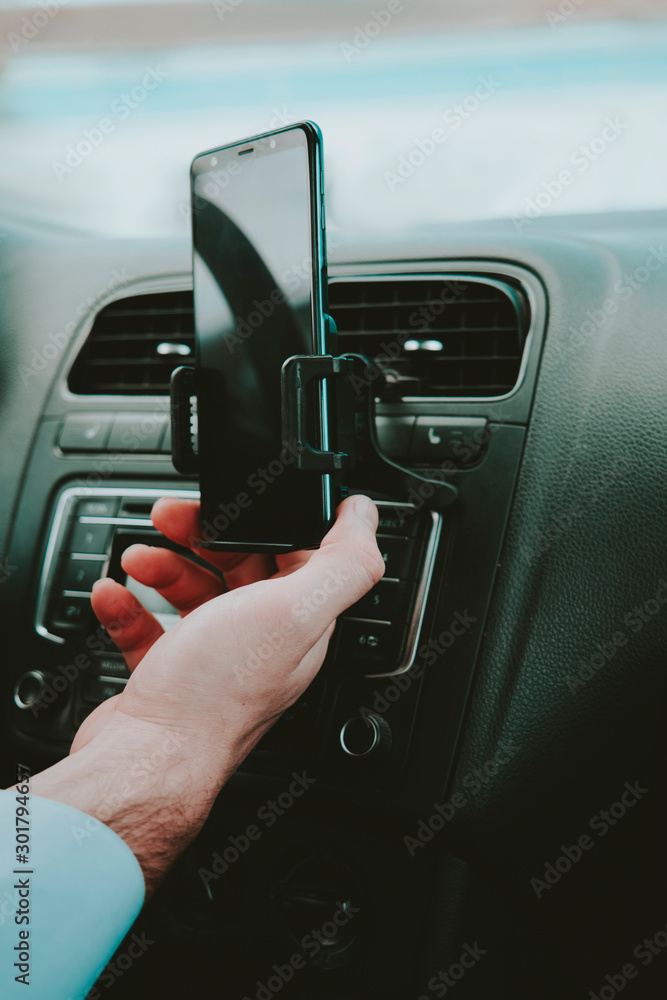A man holds a smartphone with a layout in the car on the background of clouds