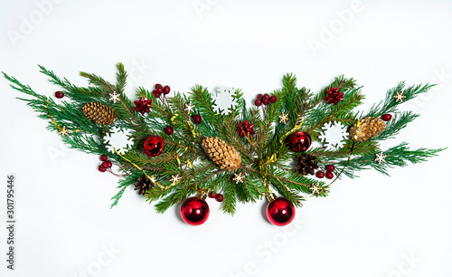 Christmas composition. The garland is made of fir and juniper branches, fir and pine cones, red berries, wooden snowflakes, red stars, balls and bells on a white background. Christmas, winter, New yea