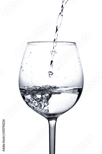Water is poured into a glass. Splash of water in a wine glass on a white background with bubbles. Studio shot. Water is the basis of life. The concept of a healthy lifestyle