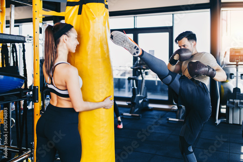 Fototapeta Young attractive woman with instructor on kickboxing training