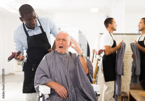 Dazed aged man with confused African hairdresser