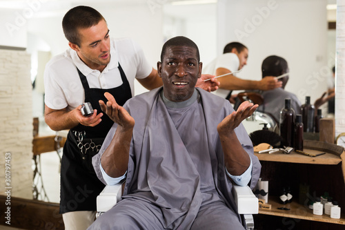 Dissatisfied African male client in hair salon