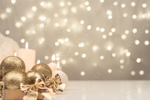 Box with golden christmas ball and candle on gold bokeh background