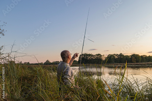 A fisherman catches fish on the shore of the pond at dawn.