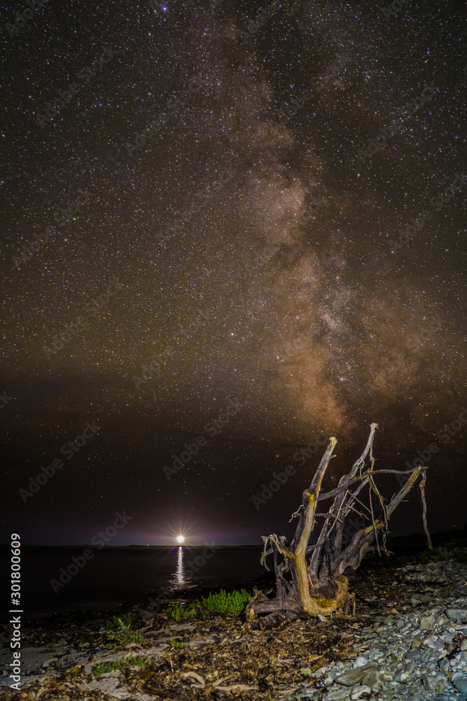 Nightscape at the beach with lighthouse and constellation