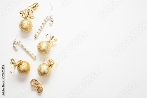 Christmas background for text is white, decorated with gold Christmas tree toys, gold ribbons and candies. The concept of a New year or Christmas.