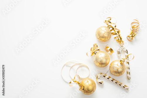 Christmas background for text is white, decorated with gold Christmas tree toys, gold ribbons and candies. The concept of a New year or Christmas.