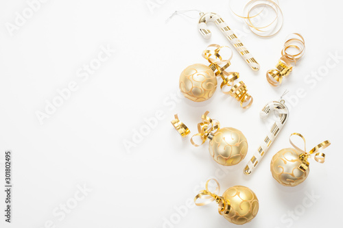 Christmas background for text is white, decorated with gold Christmas tree toys, gold ribbons and candies. The concept of a New year or Christmas.