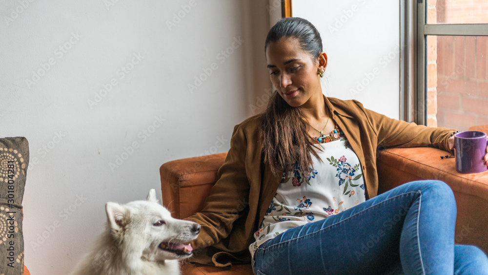 Obraz premium Beautiful latin woman resting while drinking a beverage with her pet