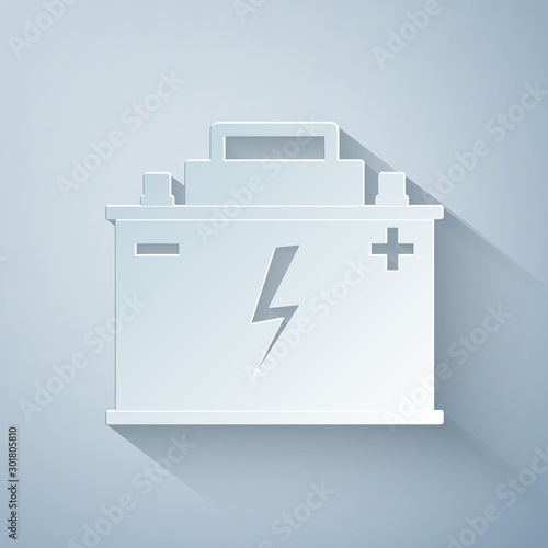 Paper cut Car battery icon isolated on grey background. Accumulator battery energy power and electricity accumulator battery. Lightning bolt symbol. Paper art style. Vector Illustration