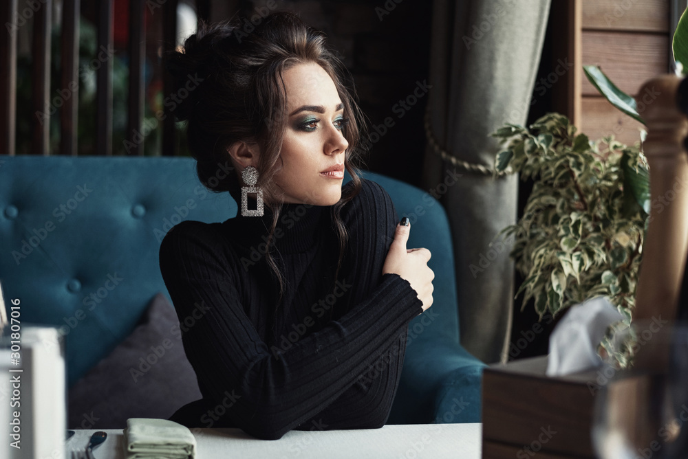 Woman sit at the table in cafe or restaurant looks at the window and drink coffee Woman sit at the table in cafe or restaurant looks at the window and drink coffee