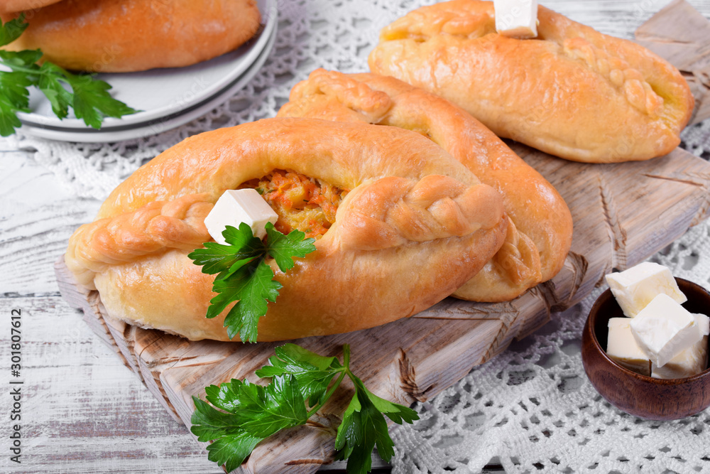 Rasstegai pie of yeast dough with meat filling on white wooden table. Traditional meal of Russian cuisine Rasstegai pie of yeast dough with meat filling on white wooden table. Traditional meal of Russian cuisine