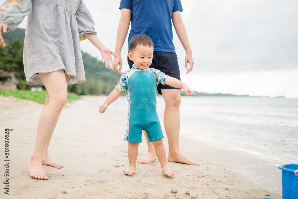 Father and Mother with boy child walk on the beach for play sand castle.parents holding hands child on the beach in summer vacation for play white sand.Family in summer vacation. Father and Mother with boy child walk on the beach for play sand castle.parents holding hands child on the beach in summer vacation for play white sand.Family in summer vacation.