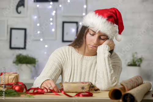 Depressed frustrated woman wrapping Christmas gift boxes, winter holiday stress concept photo