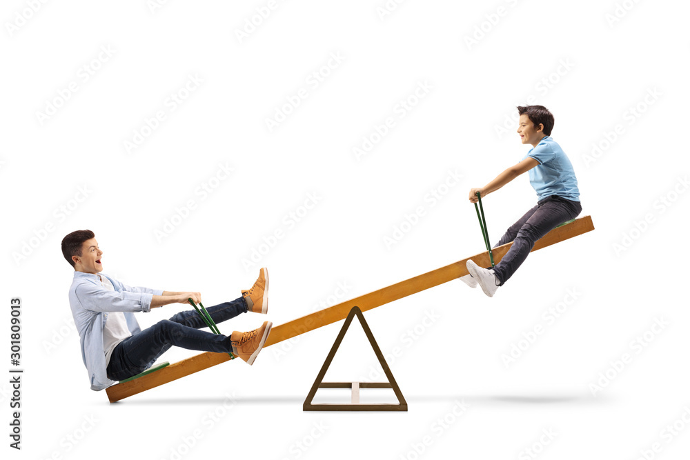Little boy and a teenager enjoying a play on a seesaw Little boy and a teenager enjoying a play on a seesaw