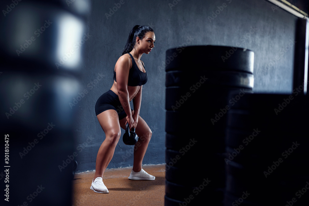 Woman fitness model make workout with weights - squat with kettlebell. Tanned sporty female, with black hair. Gym lifestyle. Woman fitness model make workout with weights - squat with kettlebell. Tanned sporty female, with black hair. Gym lifestyle.