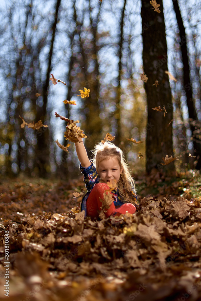 Amazing leaf. Cute girl in a big pile of foliage. Small girl smile sitting on fall leaves. Little child girl enjoy playing on fresh air Amazing leaf. Cute girl in a big pile of foliage. Small girl smile sitting on fall leaves. Little child girl enjoy playing on fresh air