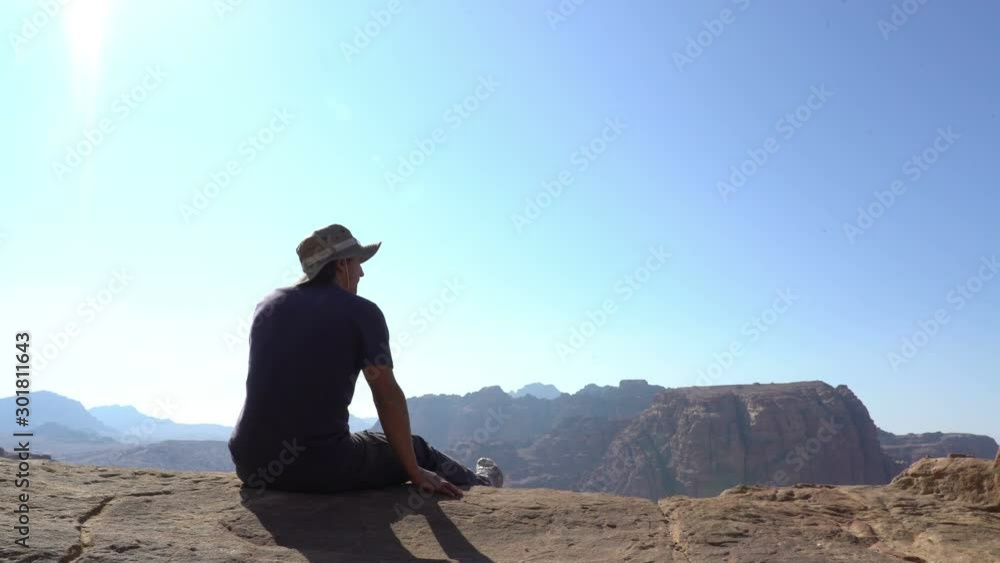 man hiking traveller sitting at the edge of mountains and looking around on beautiful lanscape man hiking traveller sitting at the edge of mountains and looking around on beautiful lanscape