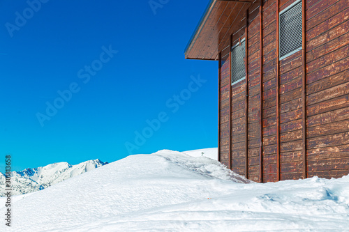 Wall of a wooden house in the mountains in the snow.