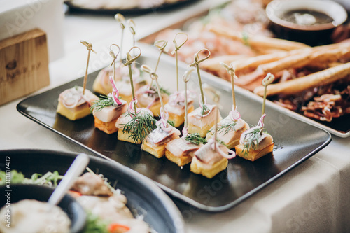 Delicious food table at wedding reception. Fish finger appetizers with onion on table at wedding or christmas feast. Luxury catering concept photo