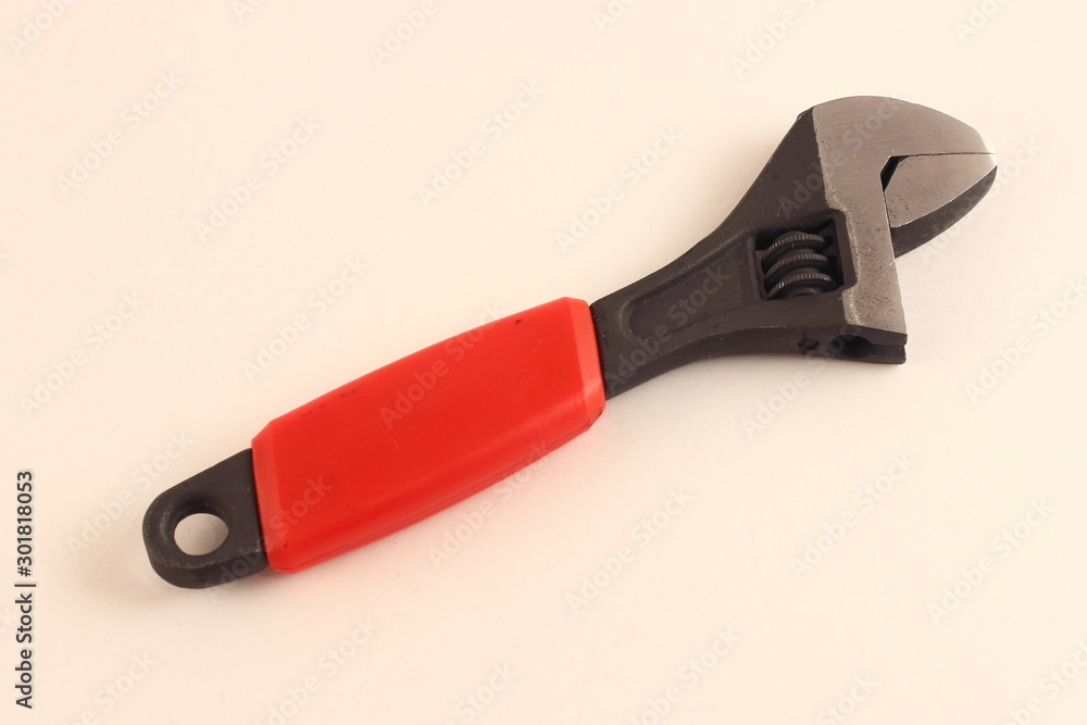 Close up adjustable monkey wrench tool with red protective handle on white background Close up adjustable monkey wrench tool with red protective handle on white background