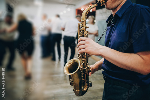 Fototapeta Musician playing sax at wedding reception in restaurant