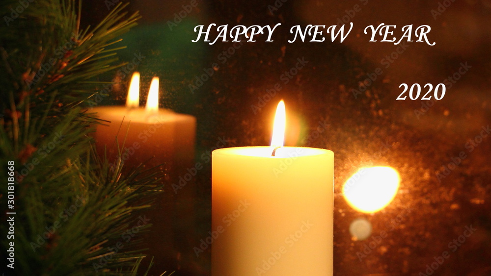 Happy new year 2020 inscription on feflective amber candle light and green fir branch background Happy new year 2020 inscription on feflective amber candle light and green fir branch background