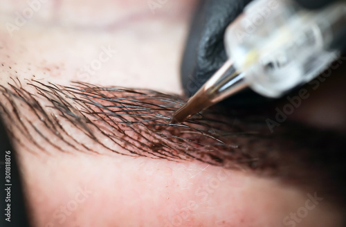 Microblading eyebrows, getting facial care and tattoo at beauty salon photo