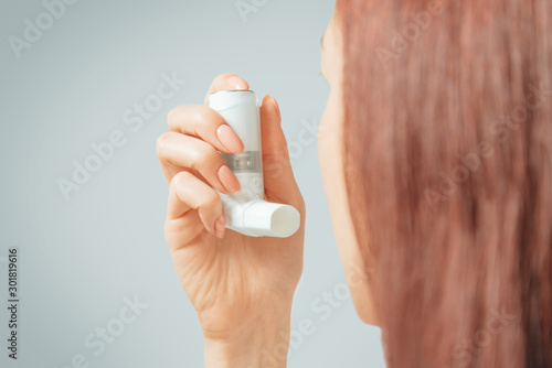Woman holding asthma inhaler to prevent an allergic attack.