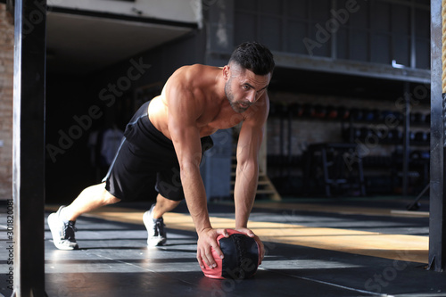 Fit and muscular man exercising with medicine ball at gym.